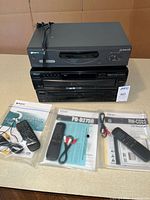 Front view of all three components stacked with remotes and manuals in foreground