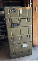 Stack of three olive drab military storage boxes showing front latches and exterior markings