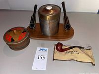 Overall lot showing pipe rack with canister, three pipes, wood box