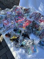 Overview of multiple bags of sealed Happy Meal toys spread on table