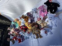 Front angled group view of approximately 40 Ty Beanie Babies bears and other animals on white backdrop