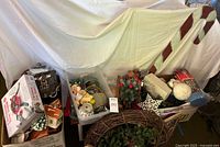 Wide view of multiple boxes and totes containing assorted Christmas decorations including large candy cane prop and wreaths