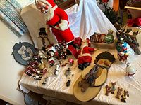 Overview of all items on tabletop including standing Santa, plaques, ornaments, carolers