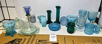 Blue/teal glass pieces including bowls, lidded candy dish, candlesticks and votives