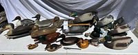 Overall view of approximately two dozen duck decoys on table