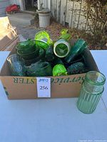 Box filled with assorted green glass pieces; ribbed tumbler outside box