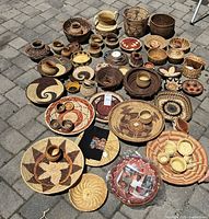 Full grouping of mixed handwoven baskets, bowls and trays on patio stones