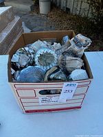 Box containing wrapped glass pieces, top view showing ruffled opalescent bowl