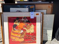 Group of framed artworks stacked; shows red background Ehling print and other frames