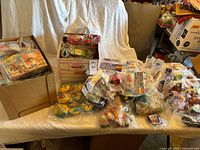 Wide view of multiple boxes and piles of sealed Happy Meal toys