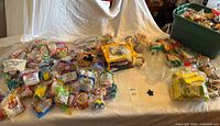 Wide view of table filled with sealed Happy Meal toys, boxed items and a bin with more toys