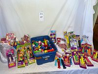 Overall lot view showing sealed PEZ packs, loose dispensers in tote, plastic bag of dispensers