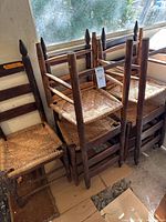 Stacked view of five ladder-back chairs with rush seats