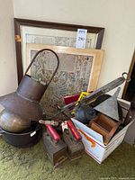 Group of items stacked, showing print, irons, lantern, dutch oven and utensils in box