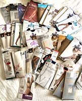 Assorted sealed pantyhose packages spread on surface showing brands and styles