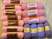 Group of all pink and lavender acrylic yarn skeins showing labels and colors