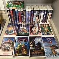 Shelf of Disney clamshell VHS tapes with two green slip-cases on top