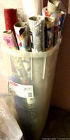 Tall plastic container holding multiple rolls of Christmas gift-wrap