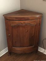 Front view of wooden corner cabinet showing single door and overall design