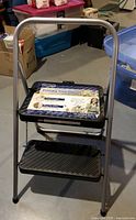 Front view of gray Cosco two-step folding stool with label attached