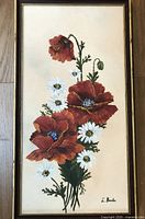 Full view of framed floral painting showing poppies and daisies with visible artist signature