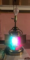 Front view of brass ship lantern lamp lit, showing red and green lens and bulb socket