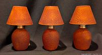 Three matching burnt-orange glass tealight lamps side by side