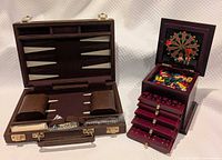 Open backgammon case beside open wood game cabinet showing drawers and contents