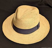 Top angled view of the Cuyana straw hat showing brim and ribbon