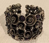 Front view of metal cuff showing spiral design with black stones and clear rhinestones