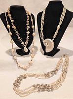 Group shot of all four shell necklaces displayed on two busts and flat surface