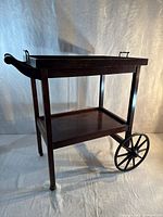 Full view of wooden tea trolley showing two tiers, spoked wheels, handle