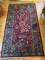 Full view of red floral wool rug on hardwood floor