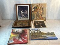 Seven of the artworks visible including framed mother-and-baby print, abstract red-gold canvas, figurative abstract canvas, landscape canvas, ornate-framed portrait print and another portrait print