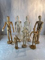 Seven wooden artist mannequins standing on bases, varying heights