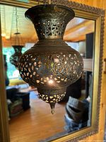 Full view of pierced brass pendant lamp hanging, showing overall shape and patina