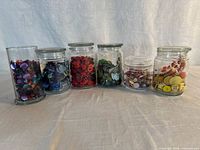 Six glass jars filled with colour-sorted buttons