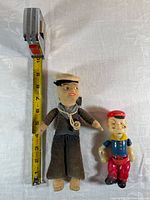 Front view of both dolls with tape for scale