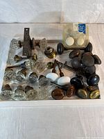Tray showing glass, brass, dark and porcelain knobs plus packaged set