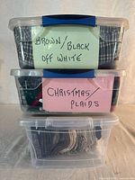 Three stacked clear plastic bins labelled for fabric colour groups