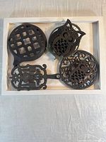 Four cast iron trivets displayed together on white tray