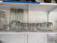Shelves holding assortment of clear glass clamp-lid jars in three size groups