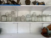 Two shelving rows showing all clear glass jars with lids