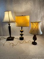 Three wooden lamps side by side showing relative size, shapes, and shades
