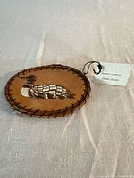 front view of birch bark plaque showing loon quillwork and edge lacing, tag visible