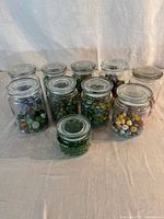 Ten glass jars filled with marbles, lids shown