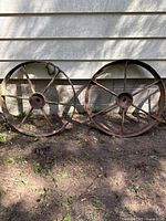 Both iron wheels leaning against wall showing size and condition