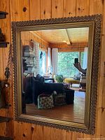 Full view of rectangular mirror on wood wall showing gold carved frame