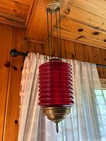 Full view of hanging red glass candle holder suspended from ceiling