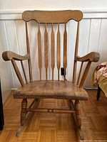 Front view of wooden rocking chair showing spindle back, seat and legs